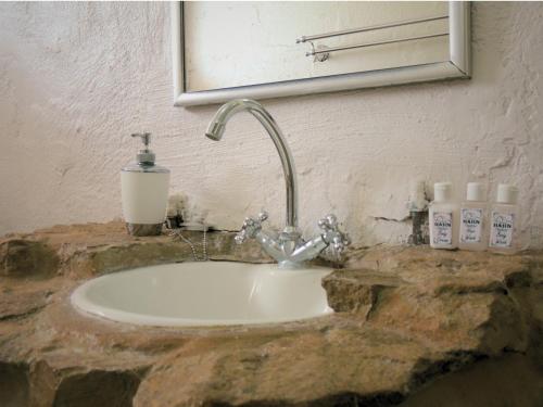 a bathroom sink with a faucet and a mirror at Barn Guesthouse in Kroonstad