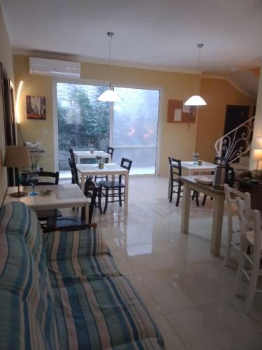 Un comedor con mesas y sillas y un gran ventanal. en b&b Denis, en Nadur