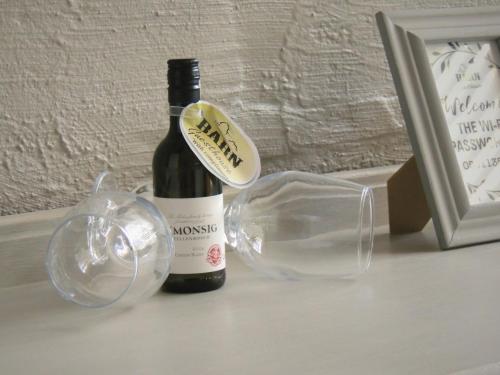 a bottle of wine and two wine glasses on a table at Barn Guesthouse in Kroonstad
