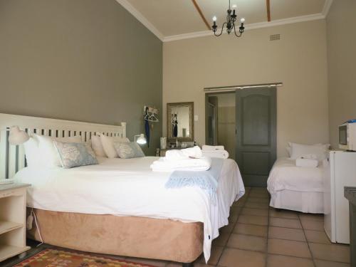 a bedroom with two beds with white sheets at Barn Guesthouse in Kroonstad