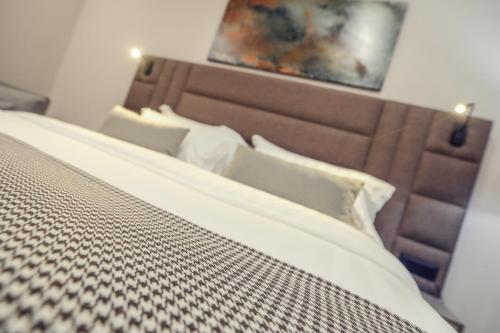 a bed with a brown headboard and pillows at Hotel Dirista in Shkodër