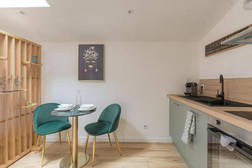 a kitchen with a small table and two green chairs at La Savane, Studio Calme & Hyper Centre Villefranche-sur-Saône in Villefranche-sur-Saône