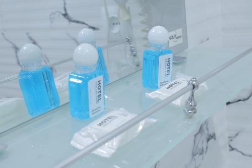 a shelf with four blue bottles on it in a bathroom at Resident Hotel in Tashkent