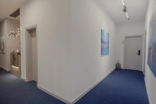 a hallway with white walls and a blue carpet at Hotel Dirista in Shkodër