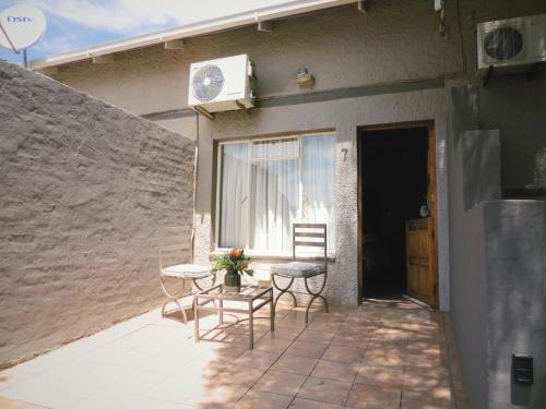 a patio with a table and chairs next to a building at Barn Guesthouse in Kroonstad