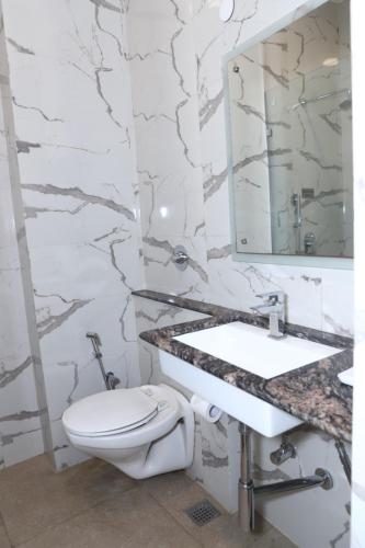 a bathroom with a toilet and a sink and a mirror at Airport Hotel in New Delhi
