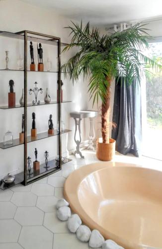 La salle de bains est pourvue d'une baignoire avec un palmier. dans l'établissement Maison de charme à Reugny avec jardin et vue sur montagne, à Chançay
