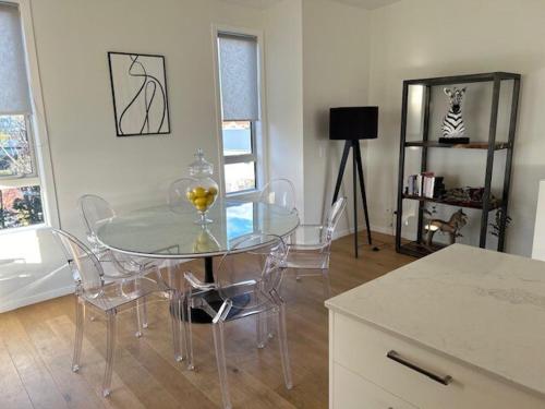 a dining room with a glass table and chairs at Stunning executive family home! in Paraparaumu
