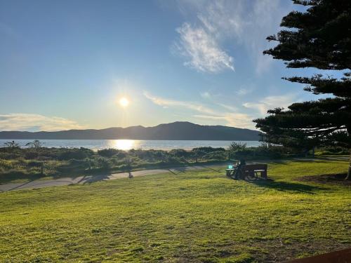 a person sitting on a bench next to the water at Stunning executive family home! in Paraparaumu