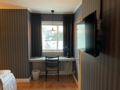 a room with a desk with a chair and a window at Hotell Örnen in Torsby