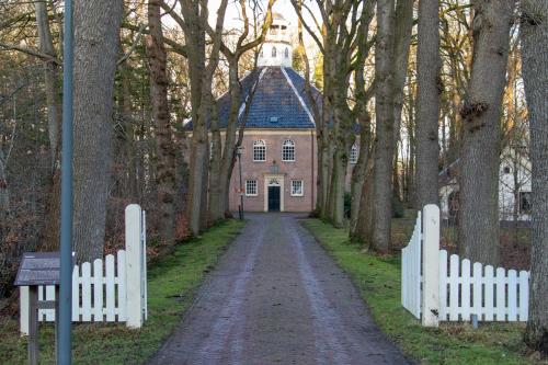 a road leading to a house with a white fence at De Consistorie in Veenhuizen