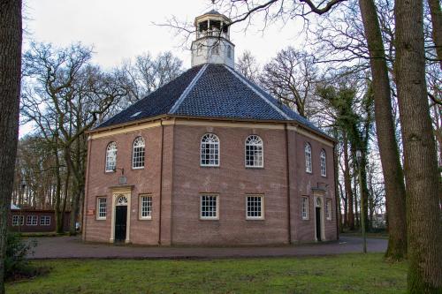 a large brick building with a clock tower on top at De Consistorie in Veenhuizen
