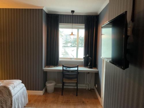 a bedroom with a desk with a chair and a window at Hotell Örnen in Torsby