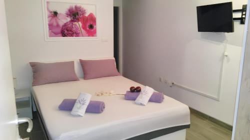 a white bed with purple pillows on top of it at Charming apartment with sea view in Sumartin - 27 sqm in Sumartin