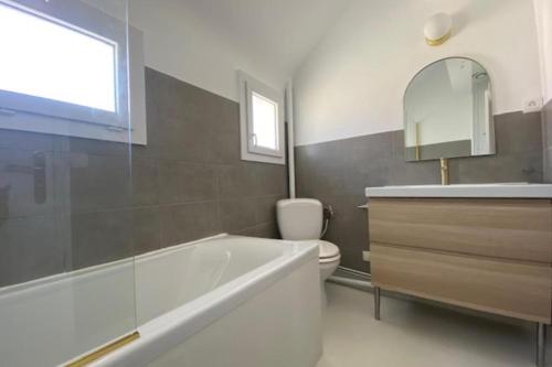 a bathroom with a tub and a toilet and a sink at La Casa Plume proche du centre et de la mer in Hermanville-sur-Mer