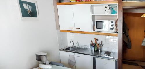 une petite cuisine avec un évier et un micro-ondes dans l'établissement Appartement au pied des pistes à La Plagne - Vue sur montagne -, à La Plagne