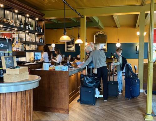 a group of people standing at a counter in a restaurant at Hotel In't Holt 1654 Grand Café & Logement in Zuidhorn