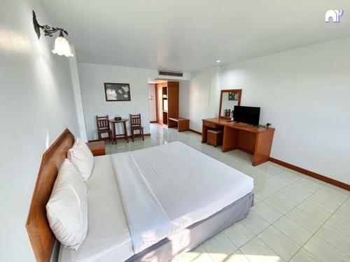 a bedroom with a white bed and a desk at โรงแรมบ้านแก้ว เรือนขวัญ in Si Sa Ket