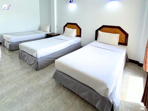 three beds in a room with white walls and tile floors at โรงแรมบ้านแก้ว เรือนขวัญ in Si Sa Ket