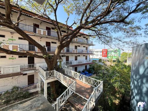 an apartment building with a tree in front of it at โรงแรมบ้านแก้ว เรือนขวัญ in Si Sa Ket