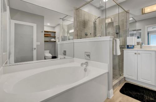 a white bathroom with a tub and a shower at Beachfront 3BDR Condo with Pool & Deck Ocean Views Ocean Blvd #102 by AvantStay in Isle of Palms