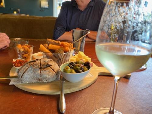 a table with a plate of food and a glass of wine at Hotel In't Holt 1654 Grand Café & Logement in Zuidhorn