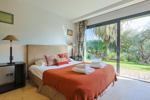 une chambre avec un lit et une grande fenêtre dans l'établissement Villa Les Rostratas, à La Croix-Valmer