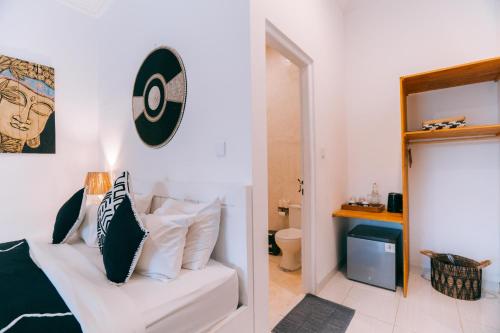 a bedroom with a white bed with black and white pillows at Sukacita Hill in Uluwatu