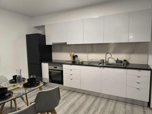 a kitchen with white cabinets and a table with chairs at Cris Place in Câmara de Lobos