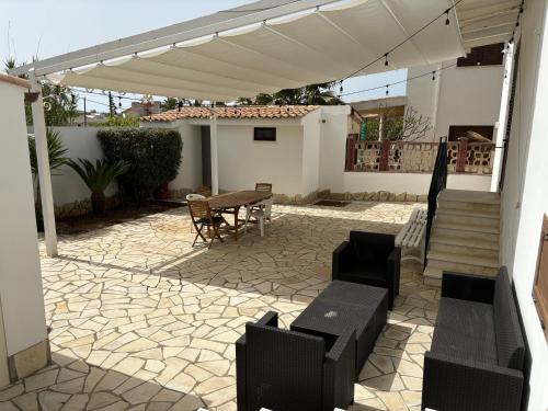 a patio with a table and a white pergola at Triscina 83 in Triscina