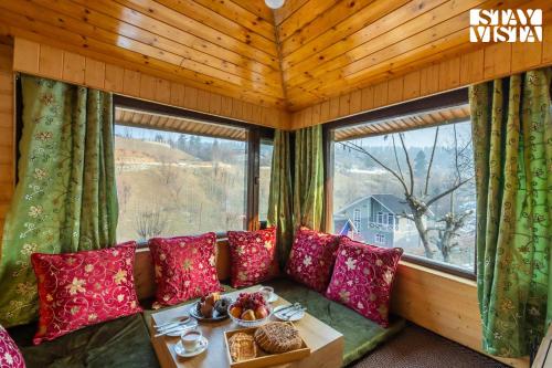 a room with a couch and a table and windows at StayVista at Riverscape with Views, WiFi, Heater in Srinagar