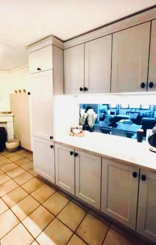 a kitchen with white cabinets and a tiled floor at Au Fil de boh'Ô in Vresse-sur-Semois