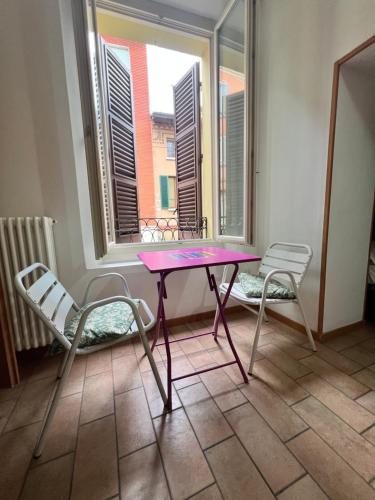 a purple table and two chairs in a room with a window at casadiviaappia in Imola