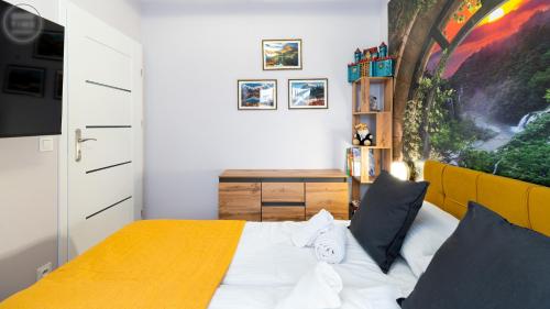 a bedroom with a bed with a yellow headboard and a desk at Apartamenty Good Time - Belle View - Centrum in Szklarska Poręba