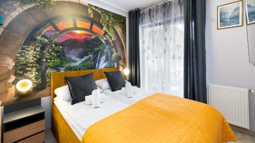 a bedroom with a yellow bed with a painting on the wall at Apartamenty Good Time - Belle View - Centrum in Szklarska Poręba
