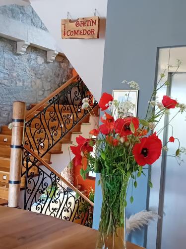 a vase with red flowers on a table next to a staircase at Antiguas Eras La Alberca in La Alberca