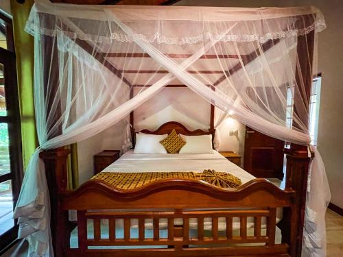 a bedroom with a canopy bed with white curtains at Heli's Villa Unawatuna in Unawatuna