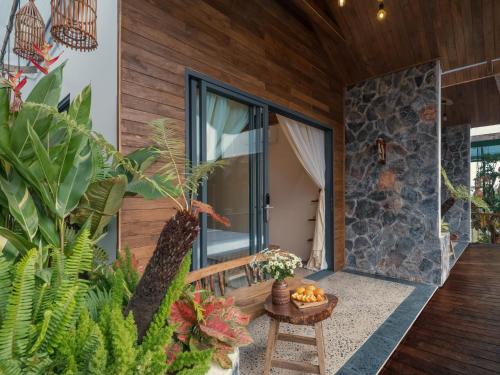 a home with a stone wall and a porch with plants at Ailee Villa&Hotel TamCoc in Ninh Binh