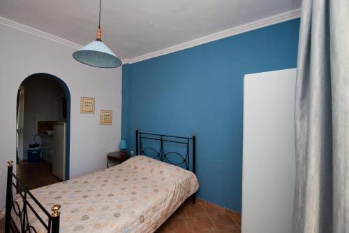 a bedroom with a bed and a blue wall at Zorbas Apartments in Volissos