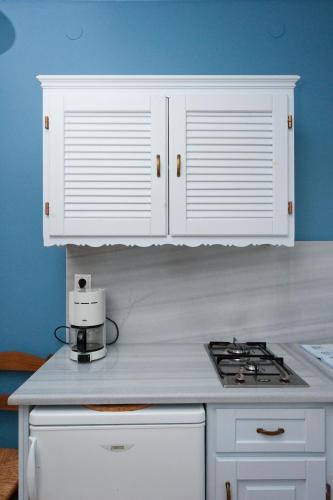 a kitchen with white cabinets and a stove top at Zorbas Apartments in Volissos