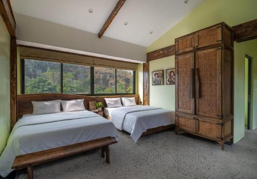 two beds in a room with windows at Ailee Villa&Hotel TamCoc in Ninh Binh
