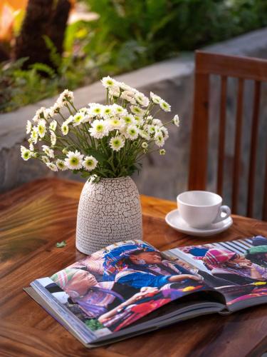 a vase with flowers on a table with a magazine at Ailee Villa&Hotel TamCoc in Ninh Binh
