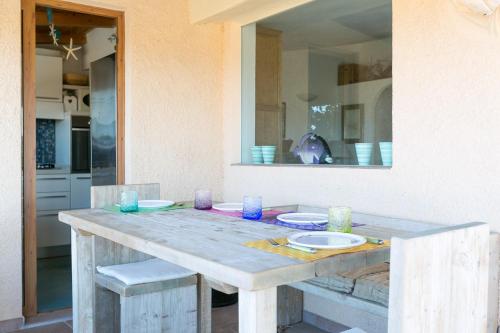 a wooden table with plates and bowls on it at Casa Azul, Seaview terrace, private parking, pool in Marinella