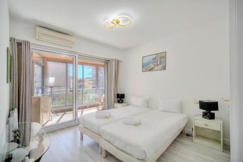 une chambre blanche avec un lit et un balcon dans l'établissement Immogroom - large apartment clim/terrace - wifi, à Cannes