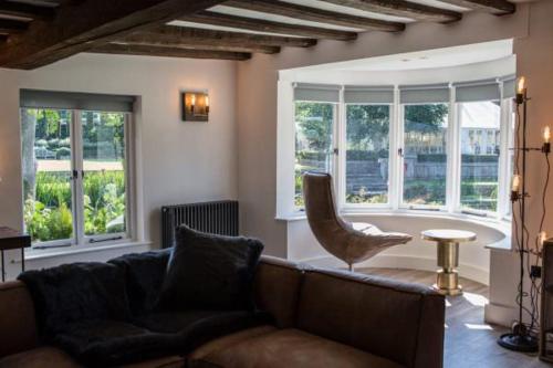 a living room with a couch and a chair and windows at Talbooth House & Spa in Dedham
