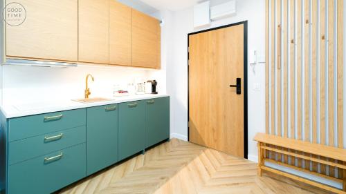 a kitchen with blue cabinets and a wooden door at Apartamenty Good Time - Belle View - Centrum in Szklarska Poręba