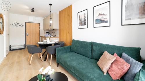 a living room with a green couch and a table at Apartamenty Good Time - Belle View - Centrum in Szklarska Poręba