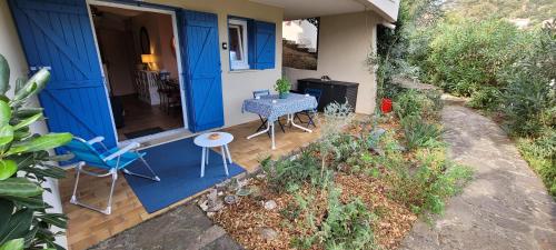 une maison bleue avec une table et des chaises sur une terrasse couverte dans l'établissement T2, Piscine en saison, Terrasse, Plage, parc privé, au Lavandou