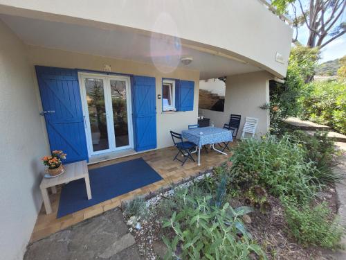 d'une terrasse avec une porte bleue et une table. dans l'établissement T2, Piscine en saison, Terrasse, Plage, parc privé, au Lavandou