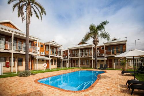 a resort with a swimming pool and palm trees at Nightcap at the Ship Inn in Busselton